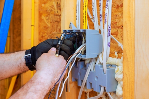 An,Electrician,Connects,Wires,In,Wall,Box,While,Wearing,Gloves